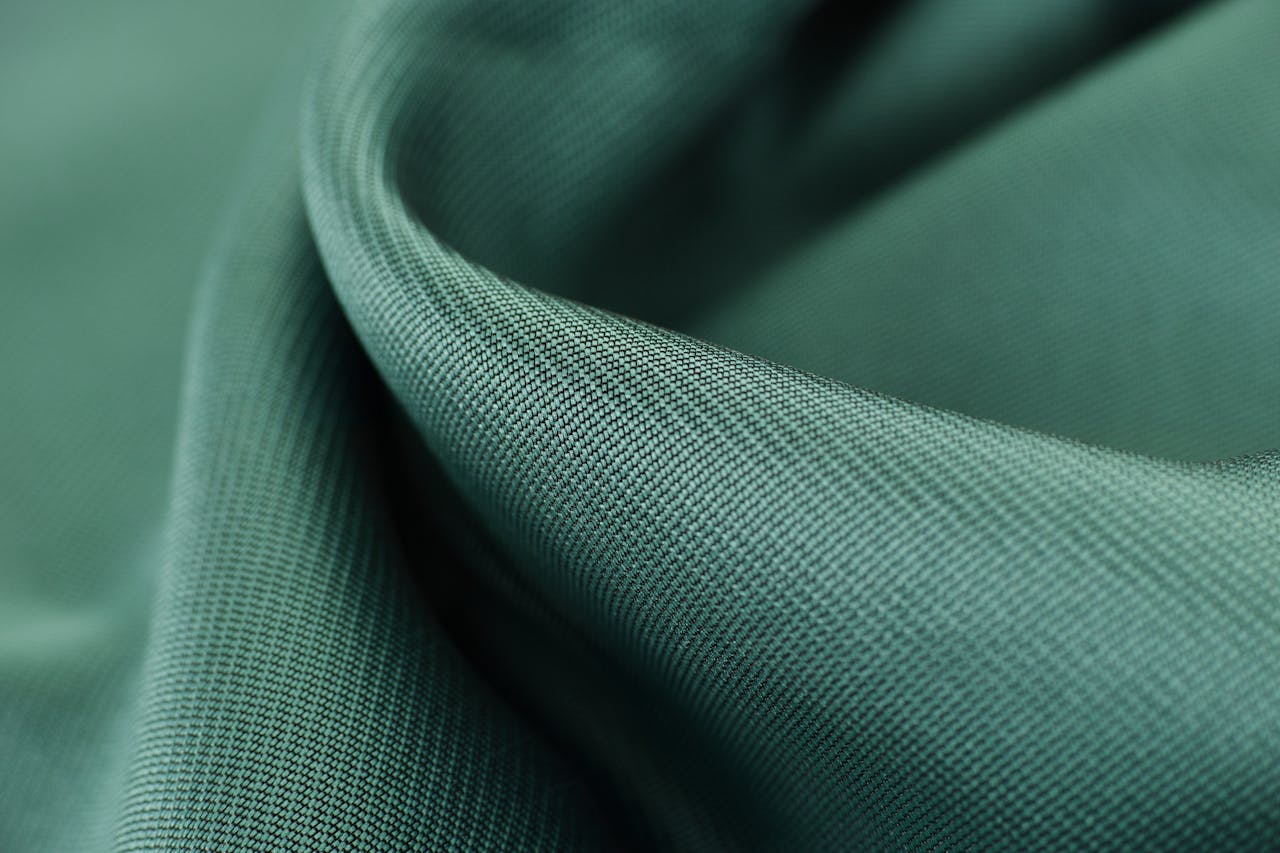 Close-up texture shot of elegant green satin fabric highlighting its smooth and soft surface.